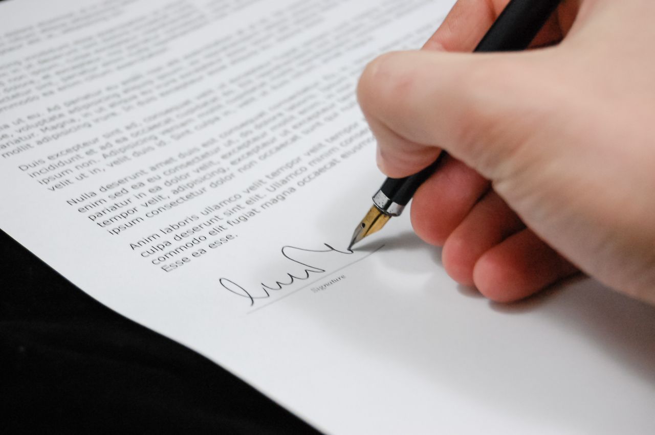Hand signing a loan agreement with a pen, the moment to know the full terms