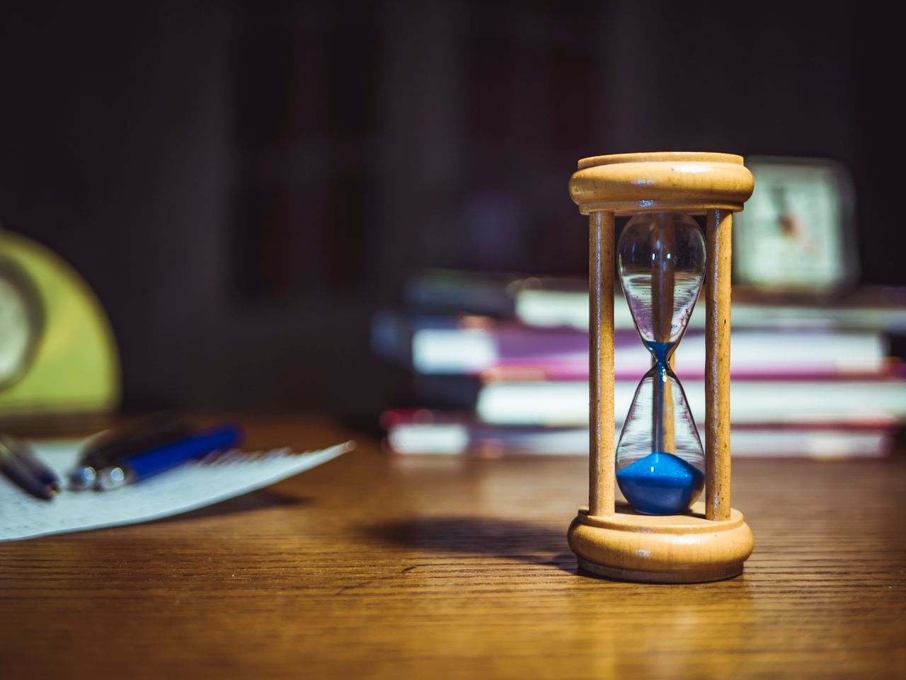 An hourglass beside overdue debt statements, representing debt timelines