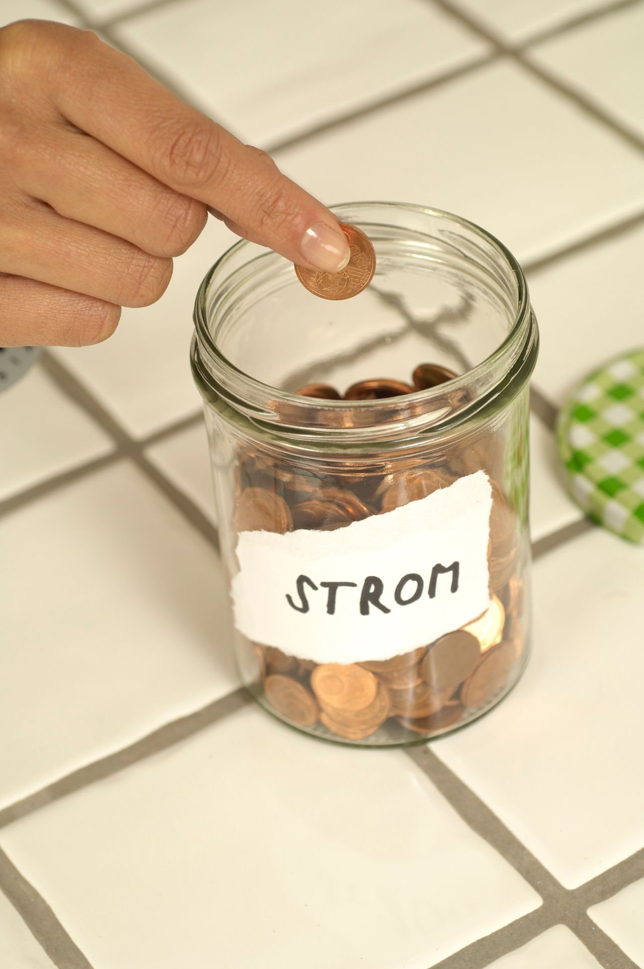 Hand adding a coin to a labeled savings jar, an emergency fund growing deposit by deposit