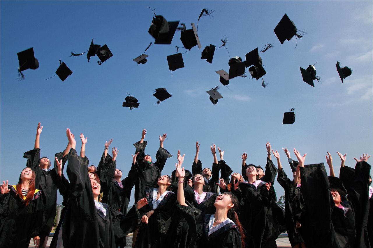 Graduates throwing caps in the air, the milestone student loans are meant to fund