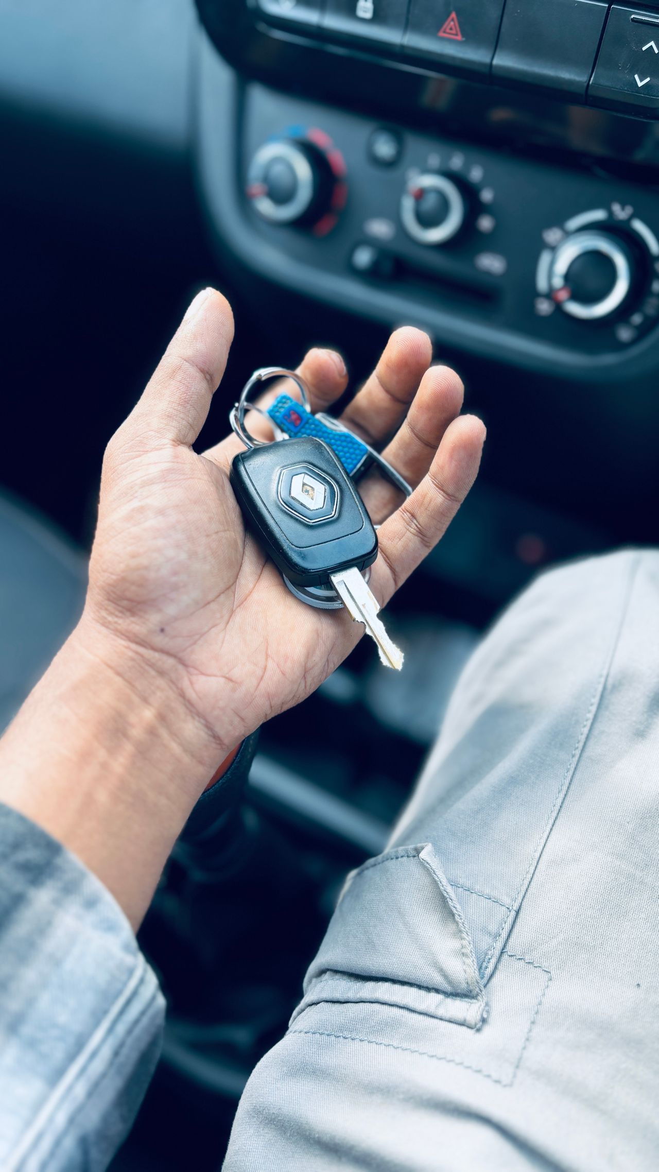 Driver holding car keys inside a vehicle, thinking through auto insurance costs