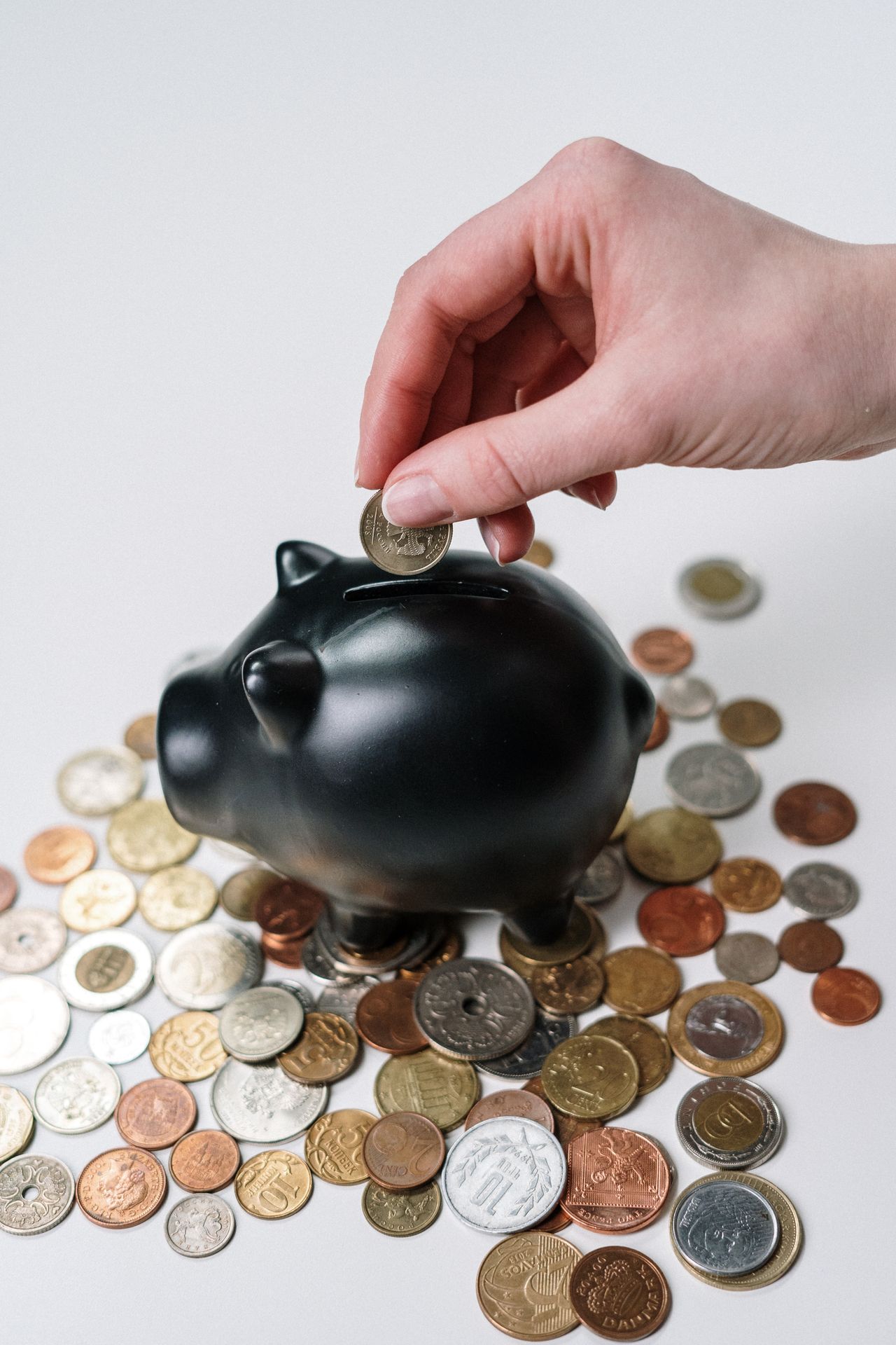 A hand placing a final coin on a shrinking stack next to a loan document, representing paying off a loan early