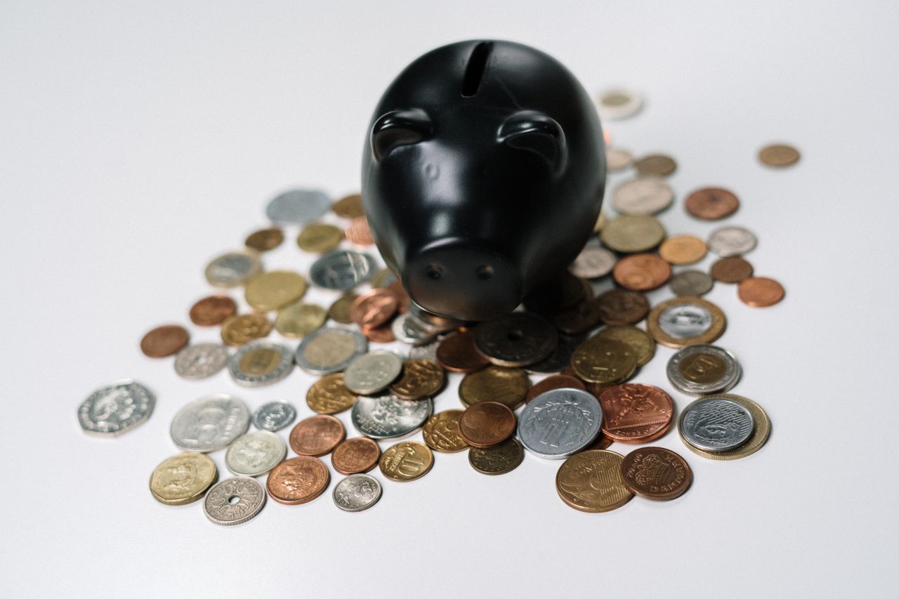 Coins gathered around a money box, representing cash saved by avoiding bank fees