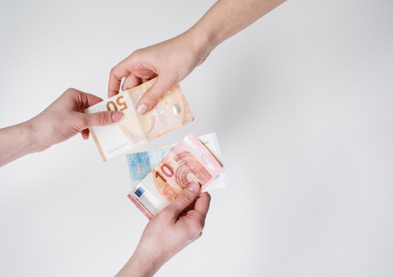 A piggy bank and coins beside a child's hand, representing a children's savings account