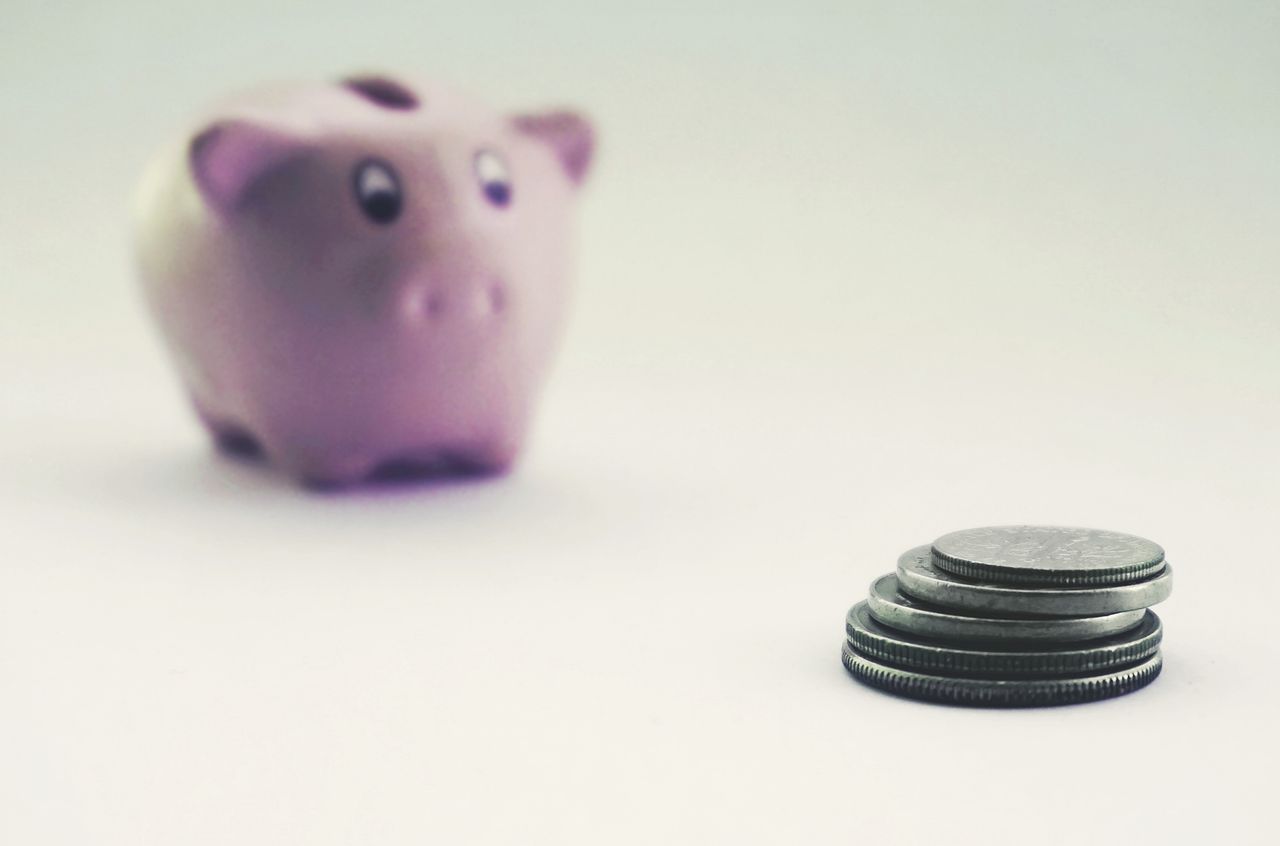 Stacked coins beside a piggy bank showing savings growing in a high-yield account