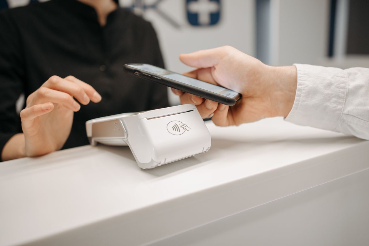 Person paying by contactless phone, earning credit card rewards on everyday spending
