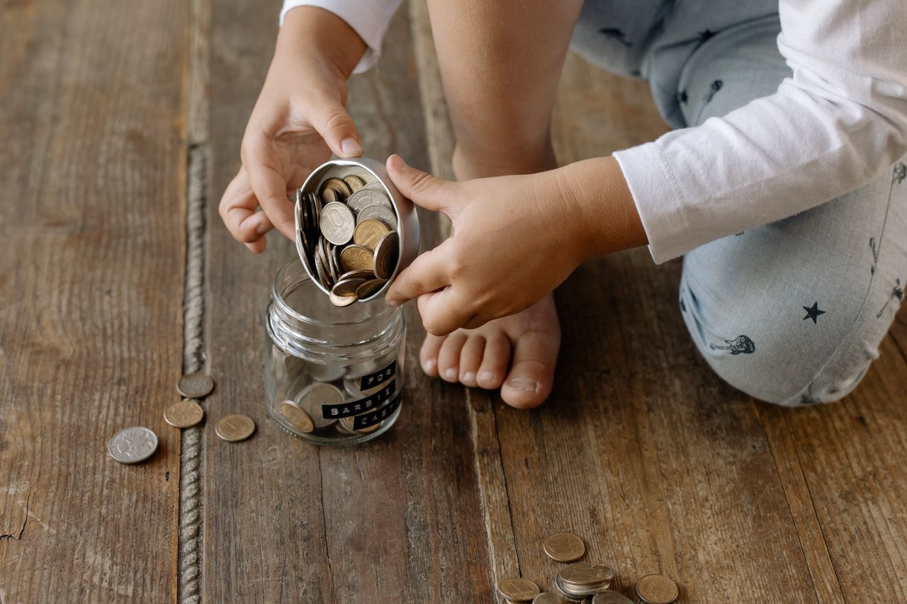 Coins being added to a glass savings jar, the habit that saving is built on