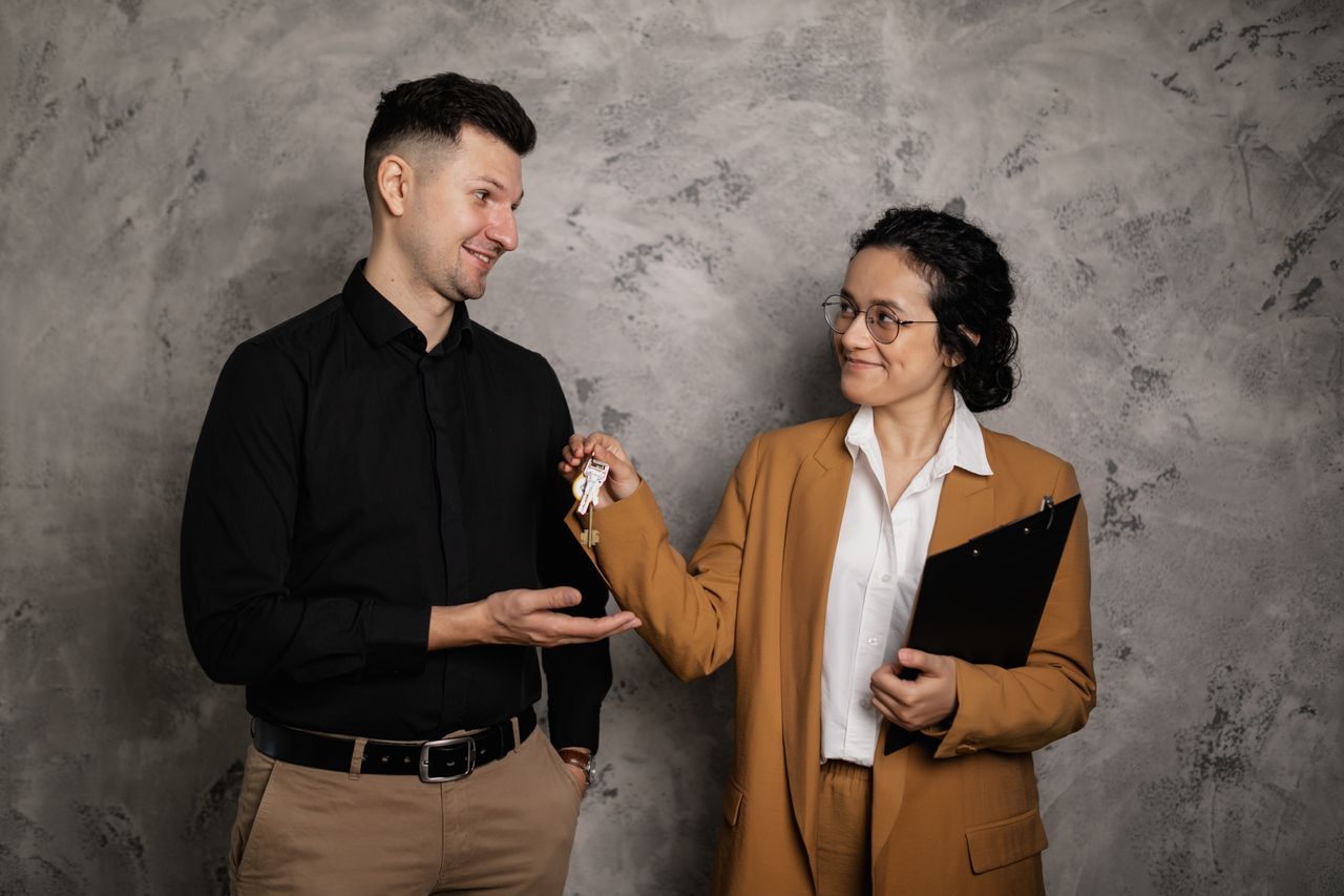 Agent handing over house keys, the moment the hidden costs of buying a home begin